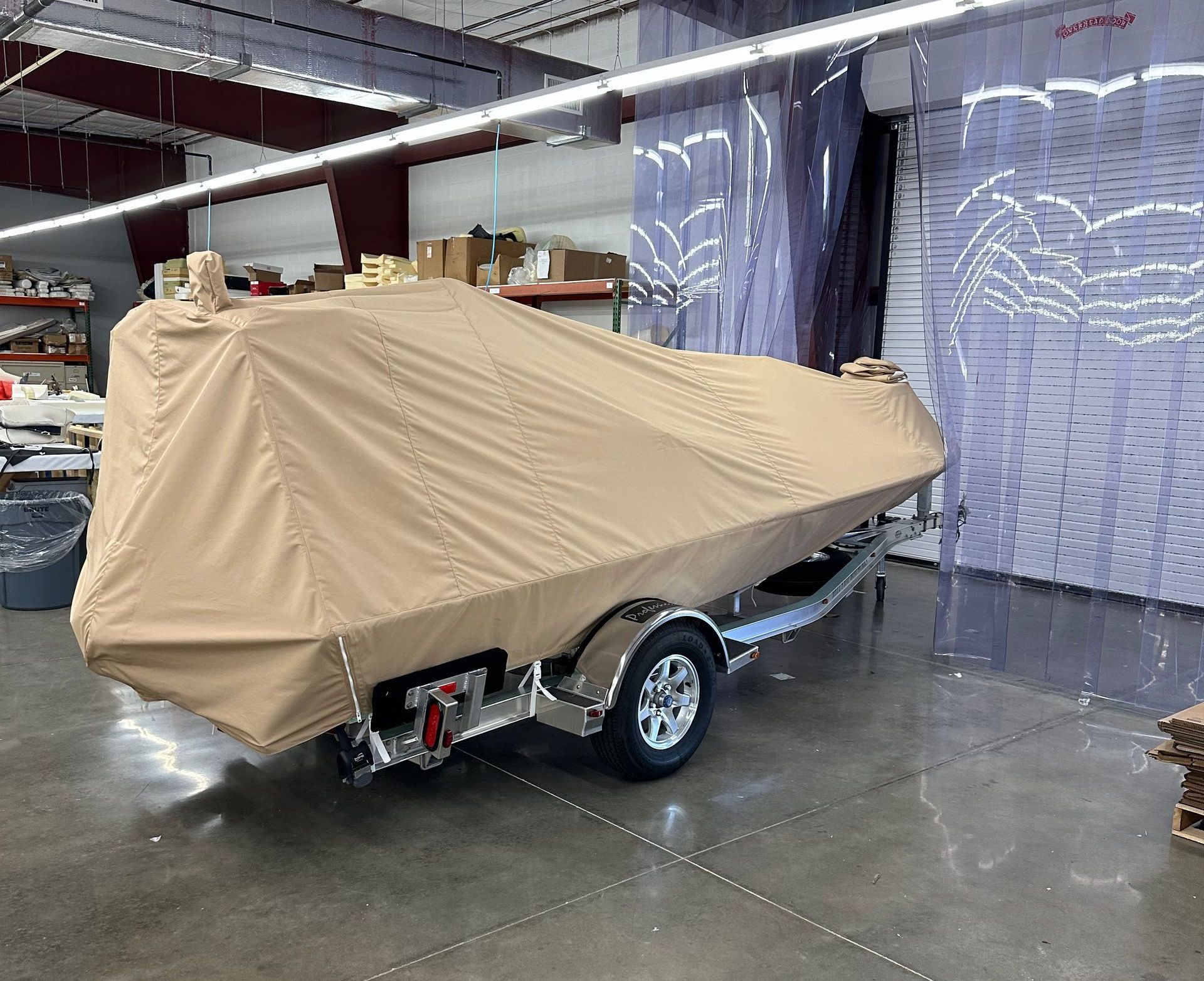 A boat is covered in a tan cover in a warehouse