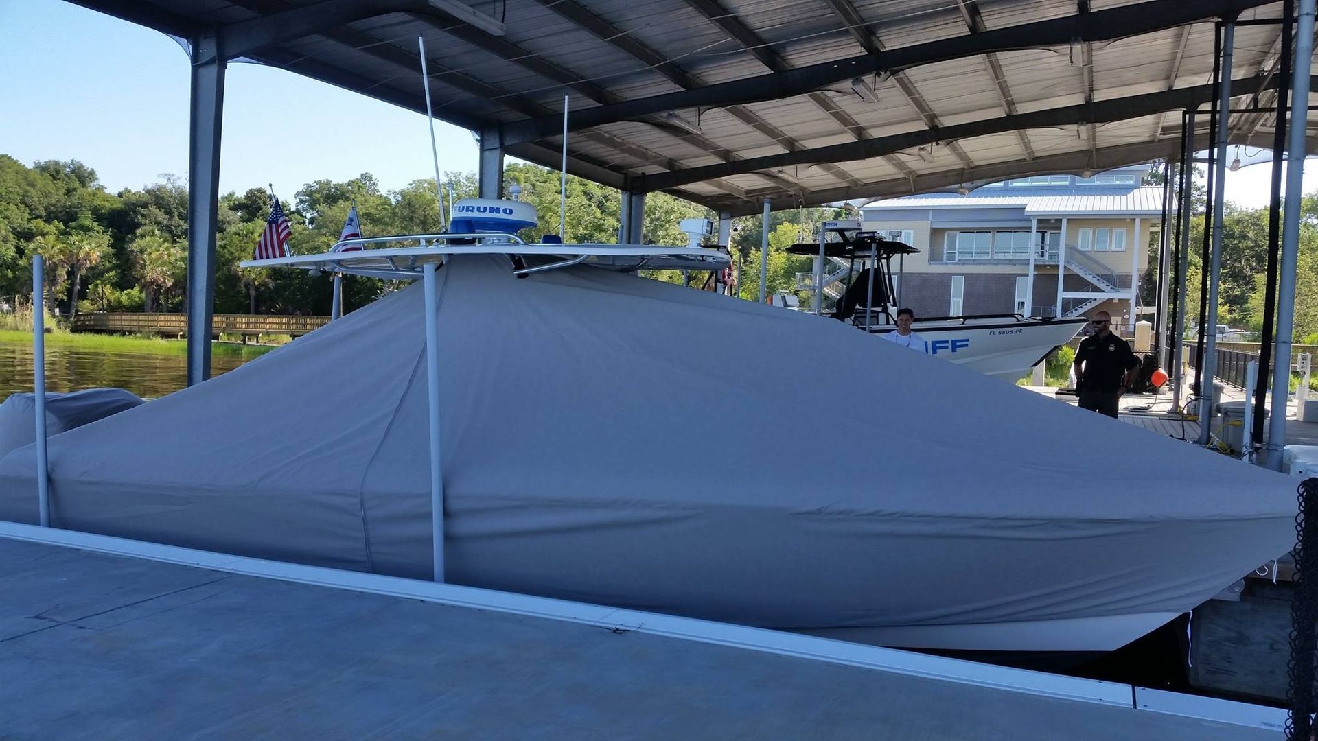A boat is covered in a gray cover in a dock.