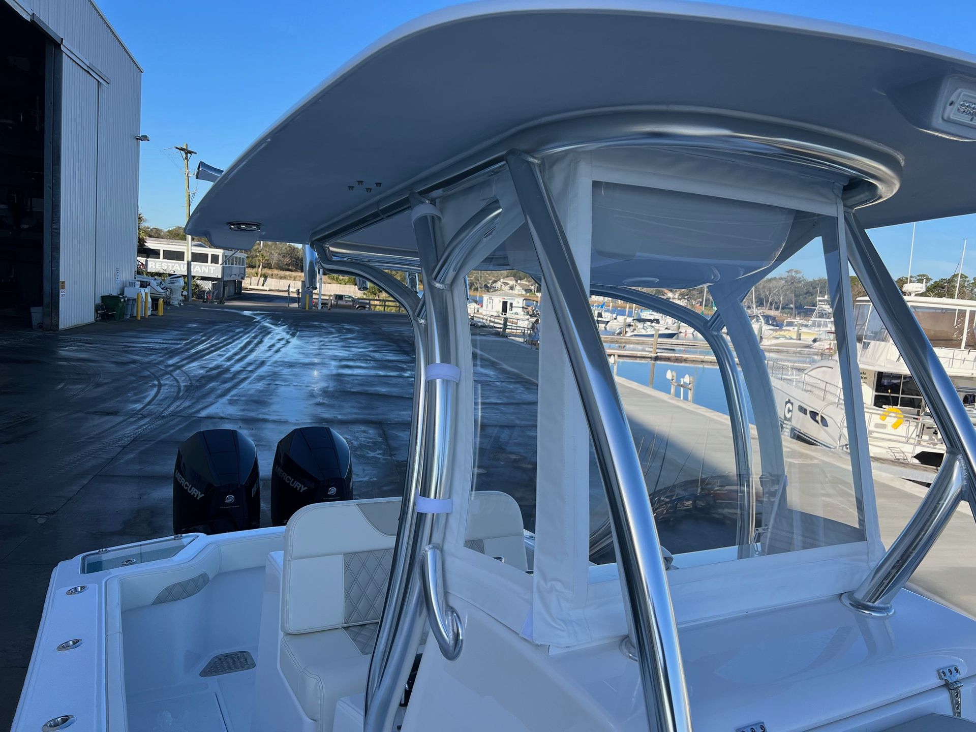 A white boat with a gray roof is parked in a marina.