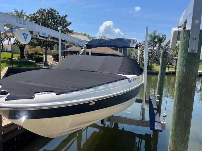 A boat is sitting on a lift in the water.