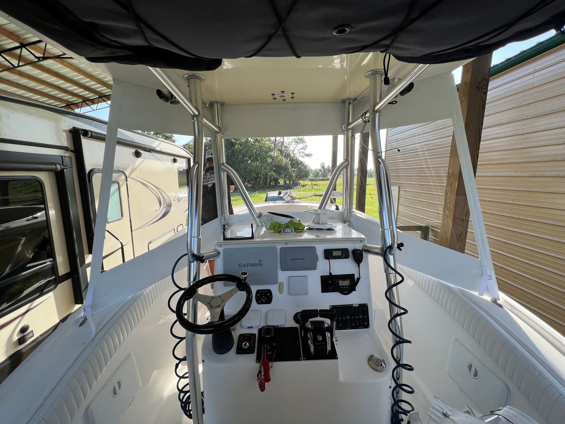 The inside of a white boat with a steering wheel and a roof.