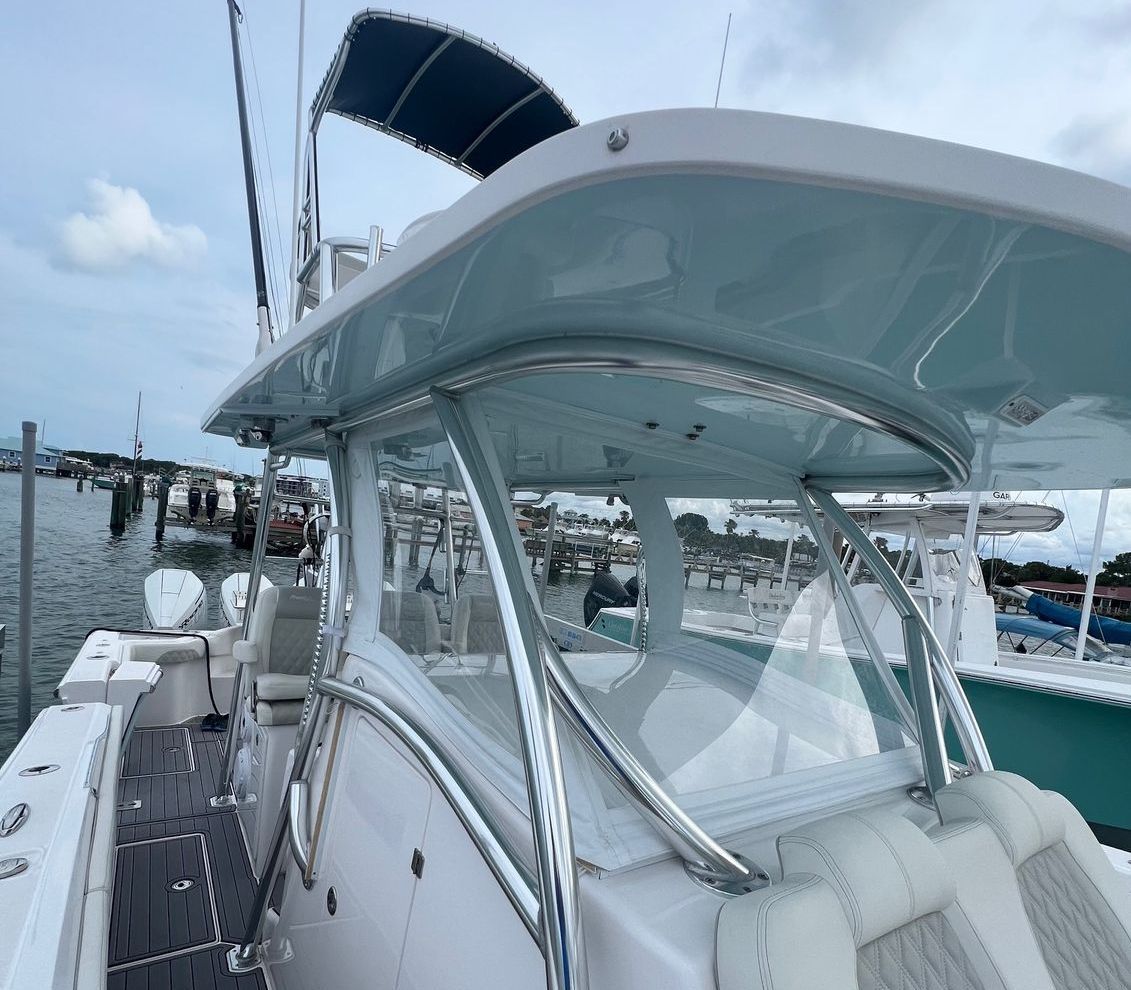 A white boat with a blue canopy is docked in a marina.