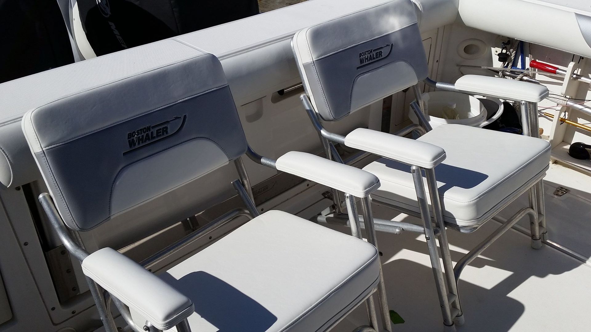 Two white chairs on a boat with the word anchor on the back