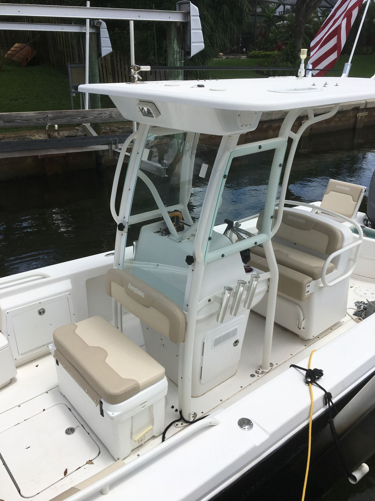 A white boat with a cooler on the deck is docked in the water.