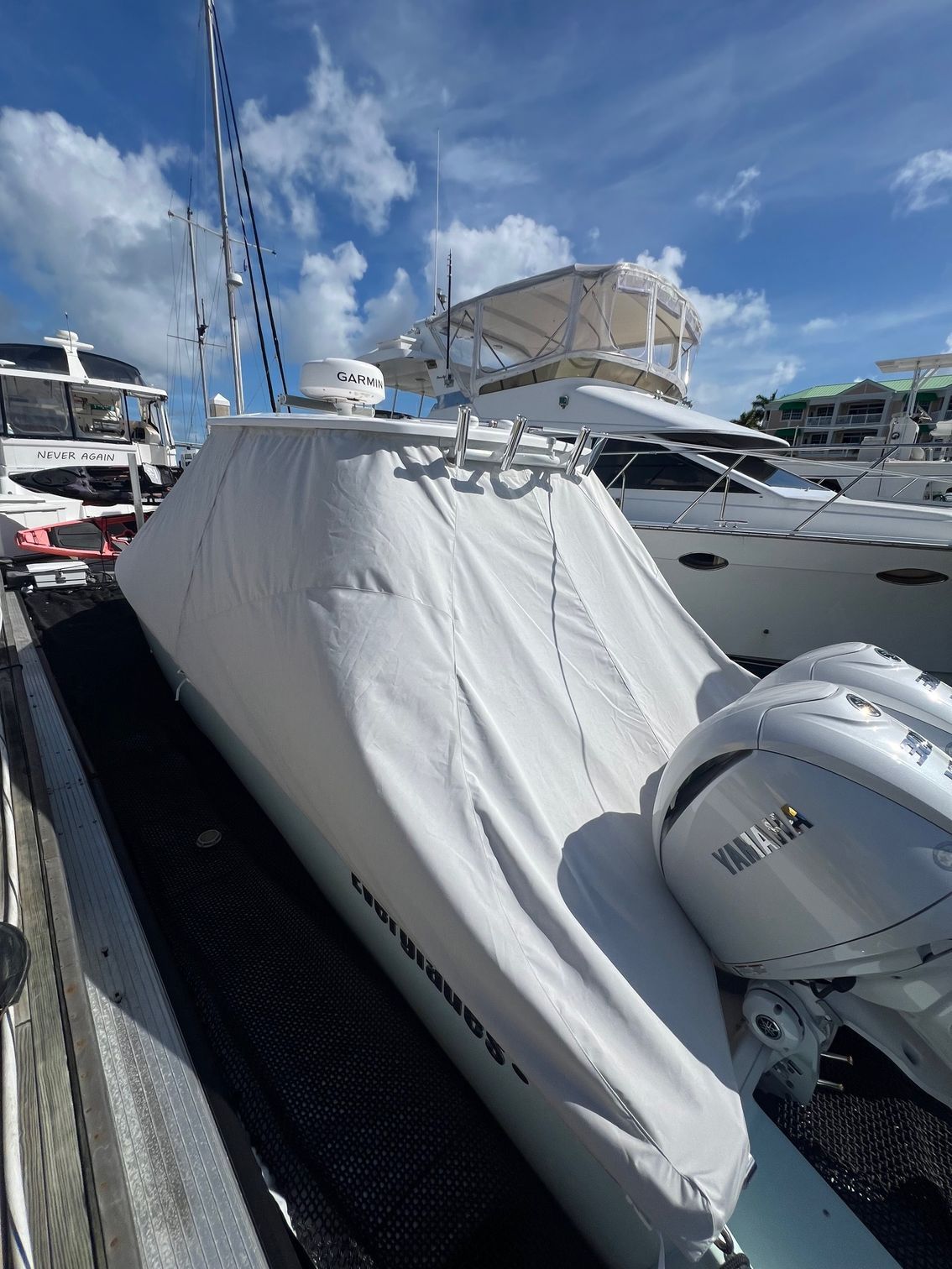 A white boat with a white cover on it is docked at a marina.