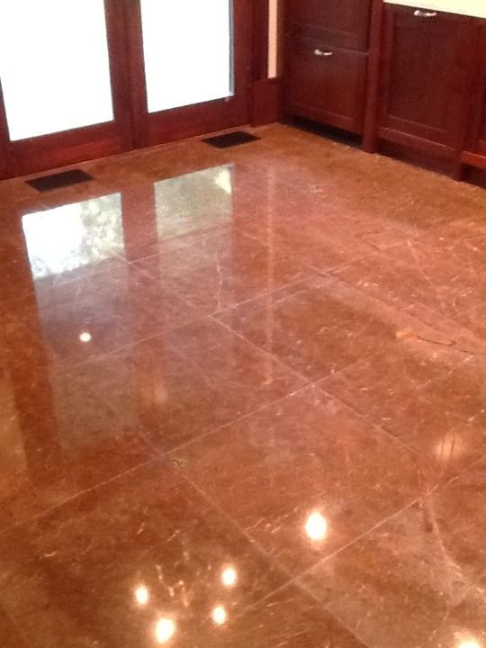 Polished brown marble floor with reflections in a wood-paneled room