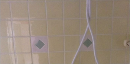 Yellow tiled wall with two green diamond accents and hanging white cords