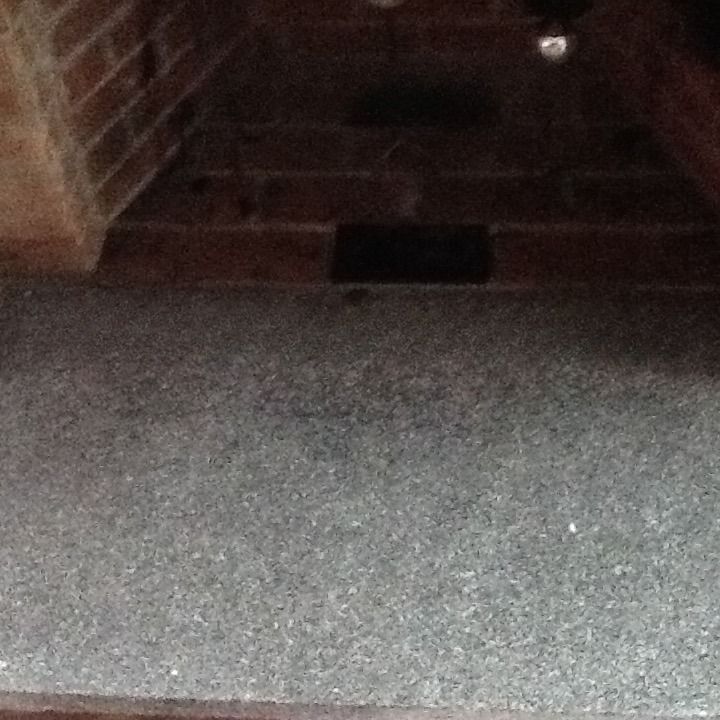 Dim brick-lined tunnel with a gray carpeted floor and a small dark opening in the back.