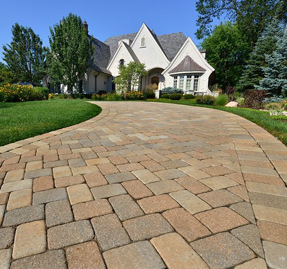 a brick driveway leading to a large white house