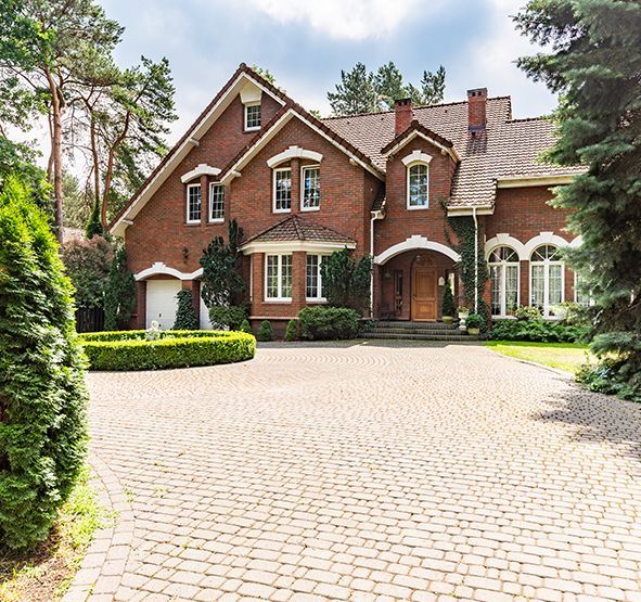 a large brick house with a brick driveway in front of it .