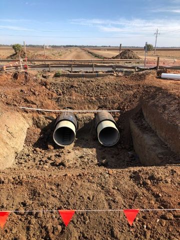 Two pipes are sitting in the dirt on a construction site.