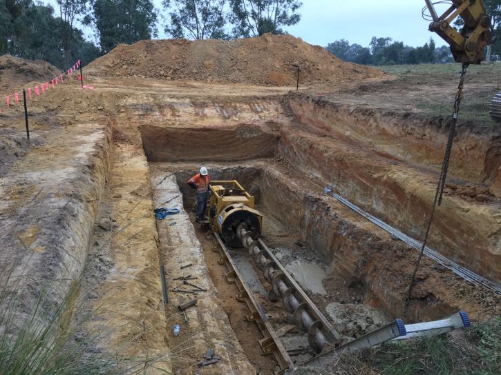A man is working on a machine in a trench.
