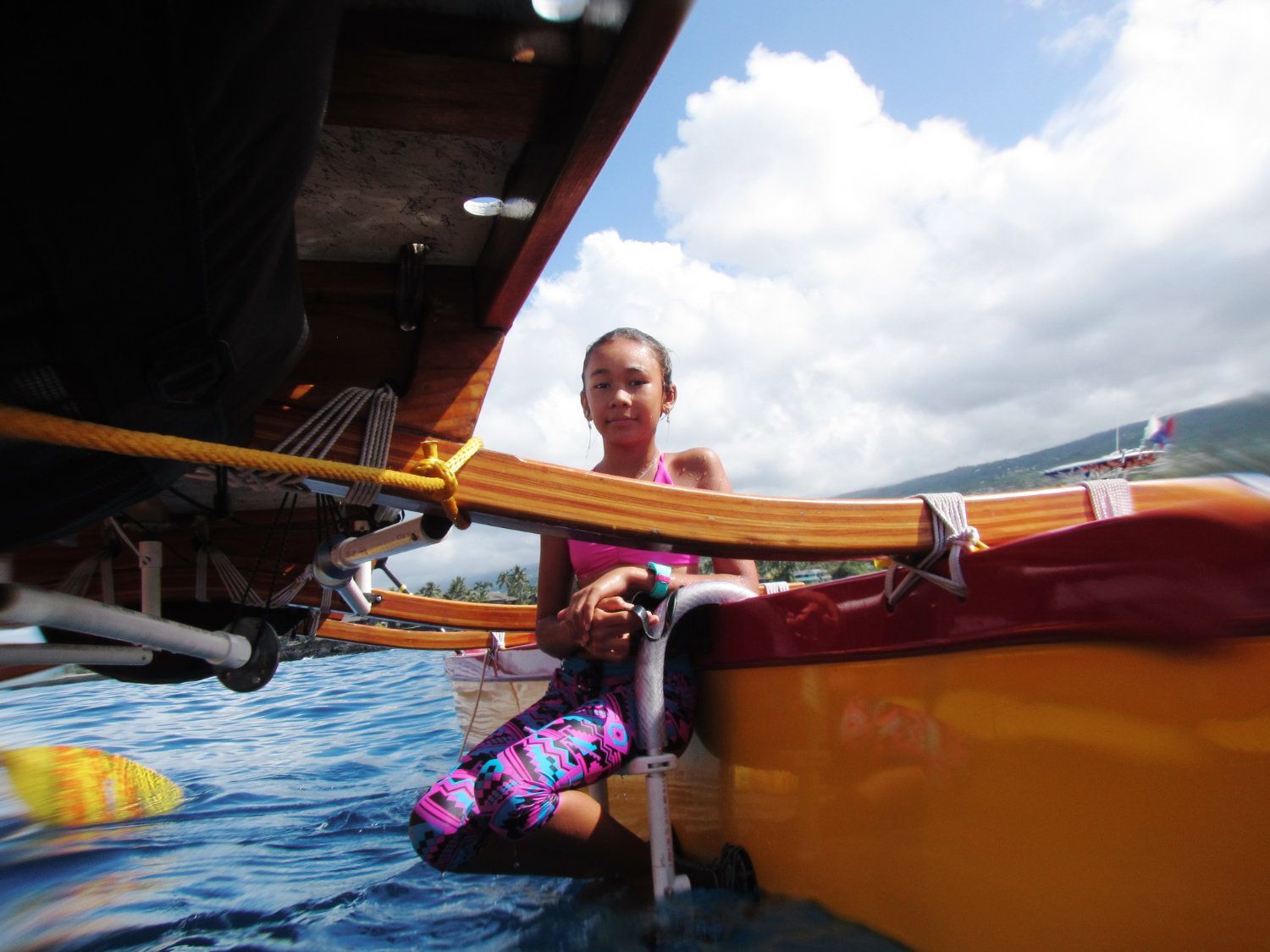 Woman in a canoe with paddle, sunny sky, ocean.