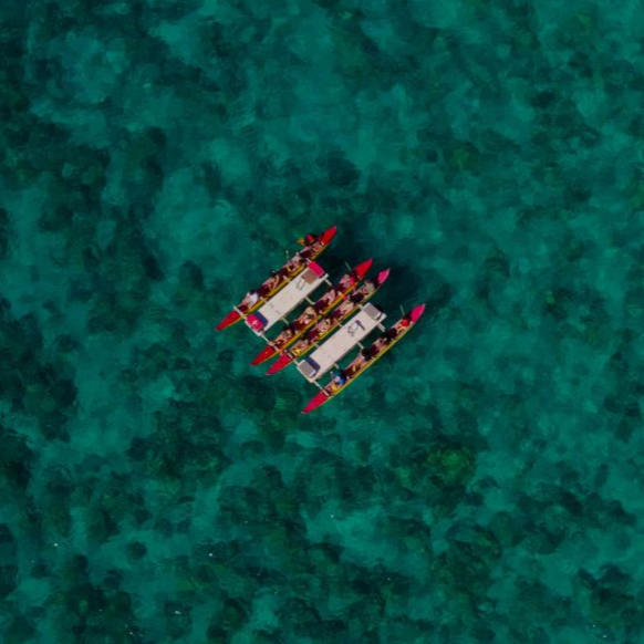 Overhead view of a catamaran with passengers on turquoise water.