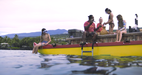 People on a yellow raft near water, mountains in background. Some are wearing snorkel gear.