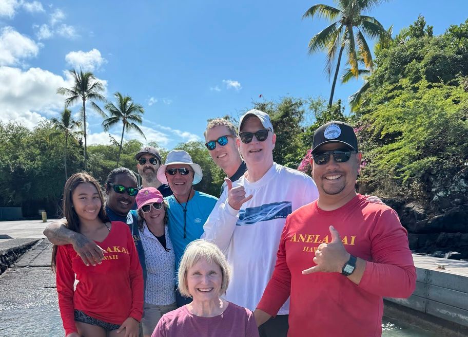 A group of people are posing for a picture in front of a body of water.