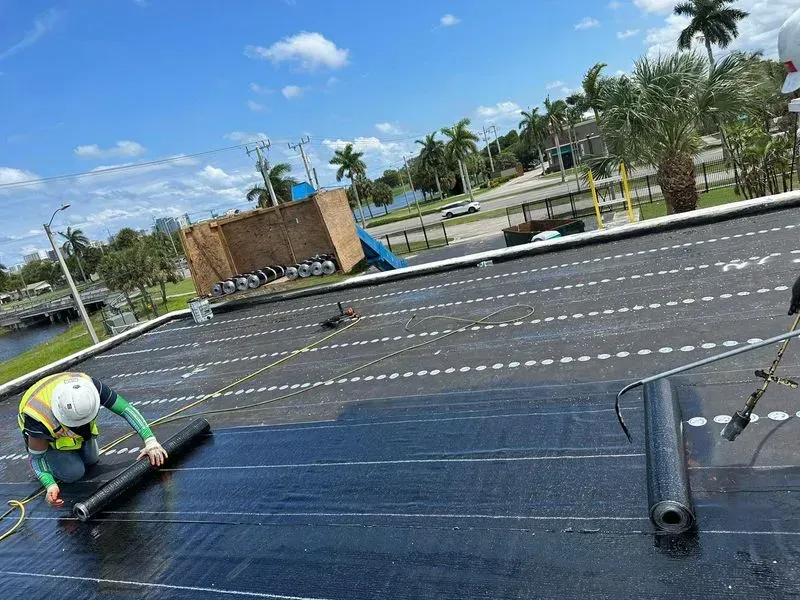 A man is working on a roof with a roller.