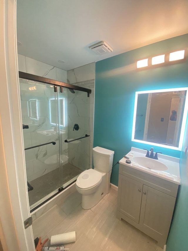 Vanity with lighted mirror and a teal accent wall, a Handyman on Demand bathroom remodel