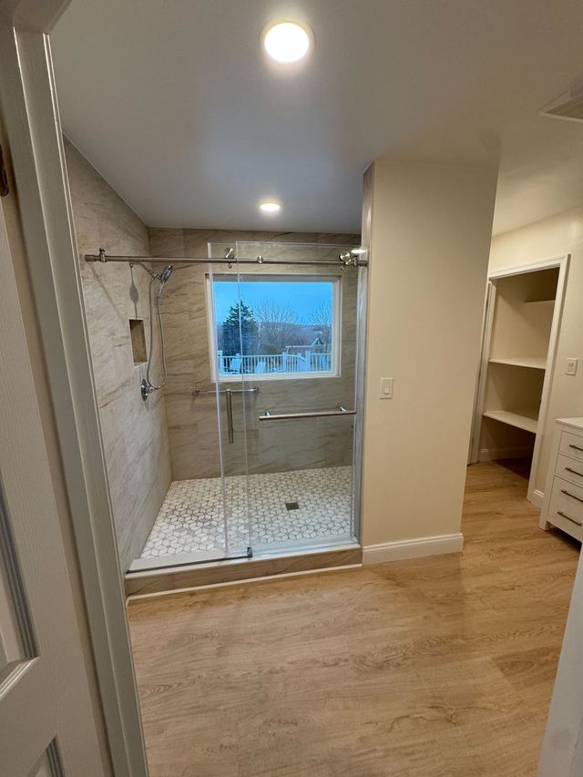 Walk-in tiled shower with a window and glass door, a Handyman on Demand bathroom remodel
