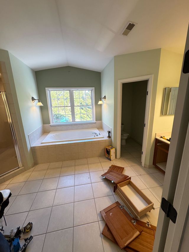 Sykesville, MD primary bathroom before remodeling, with beige tile tub deck and framed shower