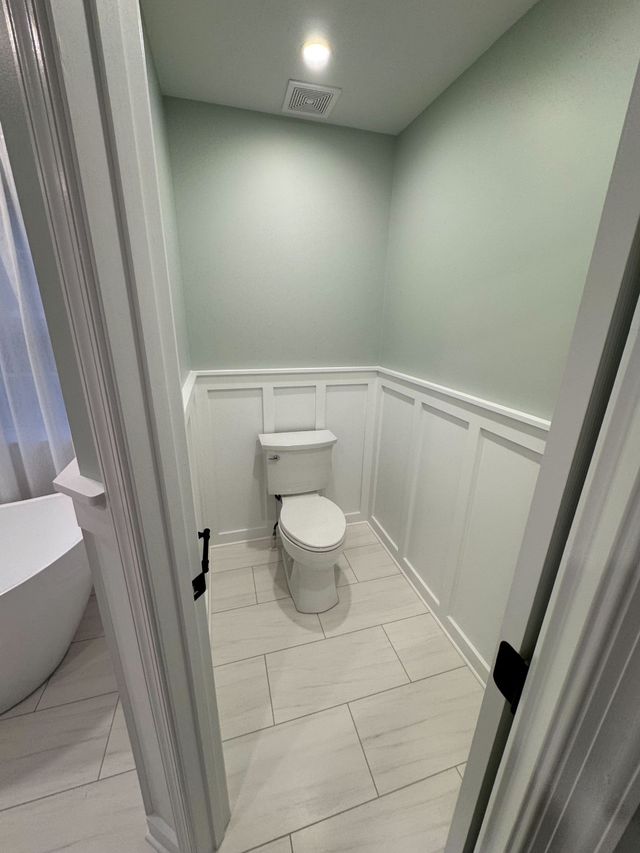 Toilet area finished with painted wainscoting and new tile floor, a Handyman on Demand bathroom remodel
