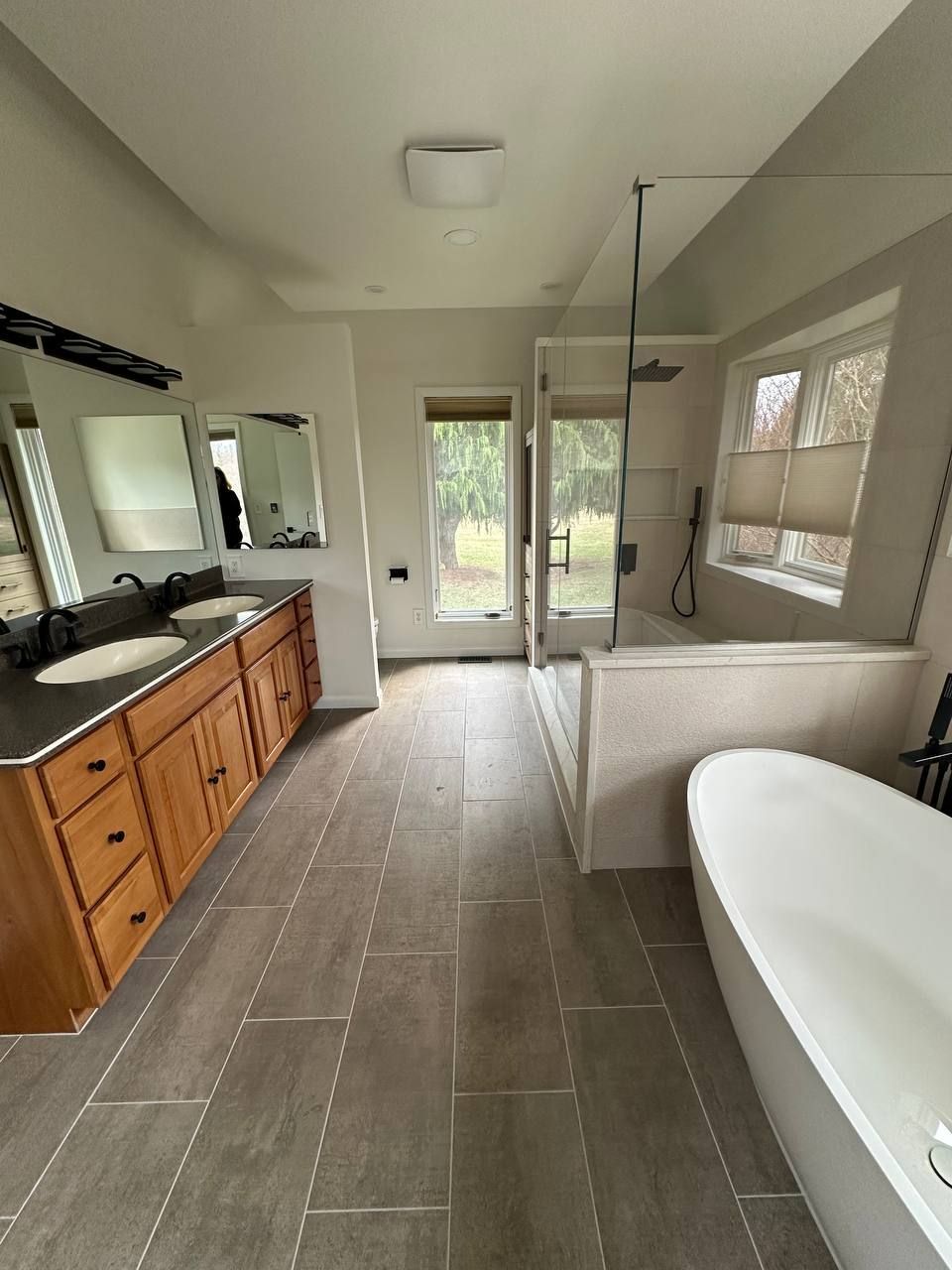 Local bathroom remodel in Baltimore County MD with double sink vanity, dark granite countertop, frameless glass shower, and freestanding tub by licensed contractor Handyman on Demand