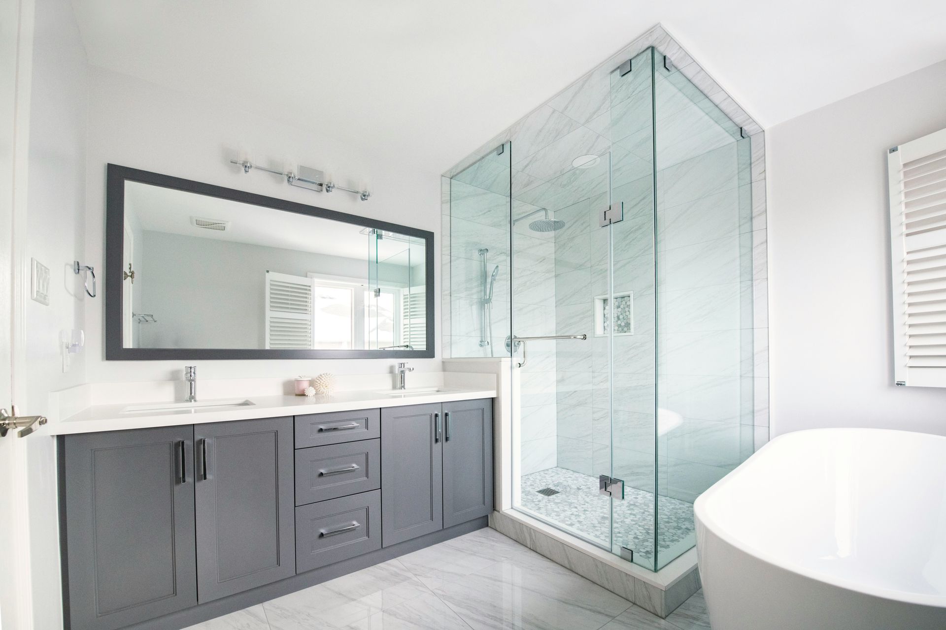 Full master bathroom remodel with gray shaker double vanity, white quartz countertop, frameless glass shower with marble tile and rain head, freestanding soaking tub, and marble floor tile — Handyman On Demand, Maryland