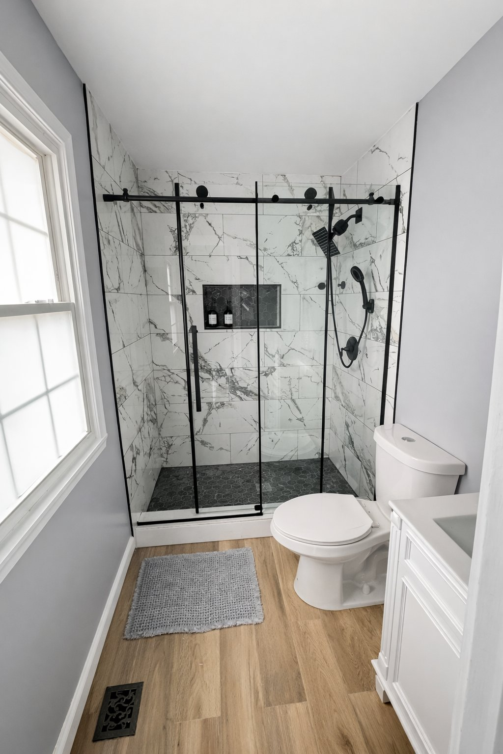 Professional bathroom remodel in Baltimore County MD featuring white marble tile shower with black sliding glass door, matte black hardware, and hex mosaic floor by Handyman on Demand