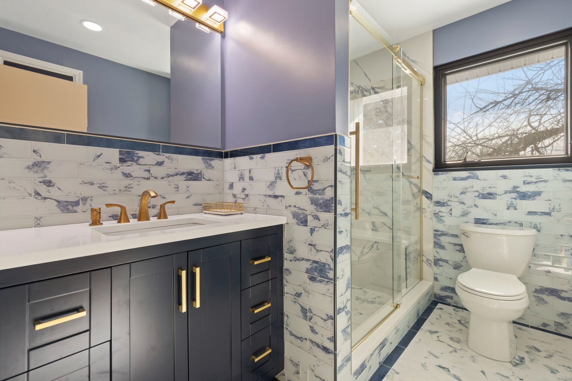Full bathroom remodel overview with vanity, walk-in shower, toilet, and marble tile by professional remodeling contractor Handyman on Demand serving Ellicott City MD