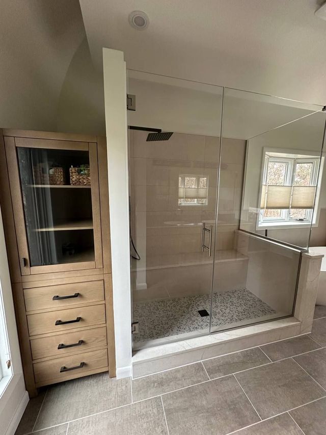 Glass shower beside a built-in linen cabinet, a Handyman on Demand bathroom remodel