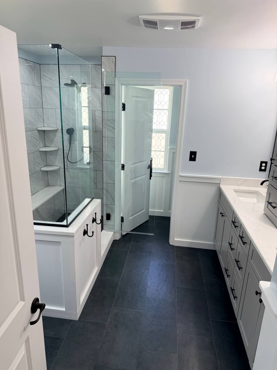Local bathroom remodeling contractor in Baltimore County MD — custom walk-in glass shower, vanity, and dark large format floor tile renovation by Handyman on Demand