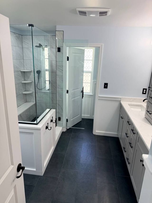 Walk-in shower and vanity over dark large-format floor tile, a Handyman on Demand bathroom remodel