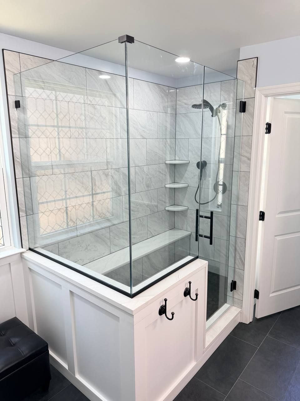 Affordable bathroom renovation in Baltimore County Maryland with frameless glass shower, marble tile surround, built-in bench, and matte black fixtures by local contractor Handyman on Demand
