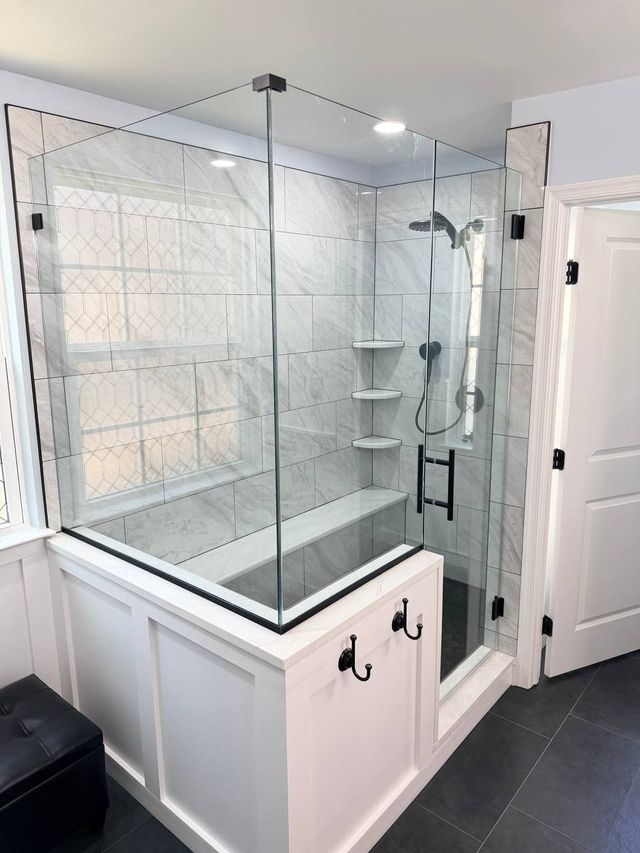 Frameless glass walk-in shower with marble tile and built-in bench
