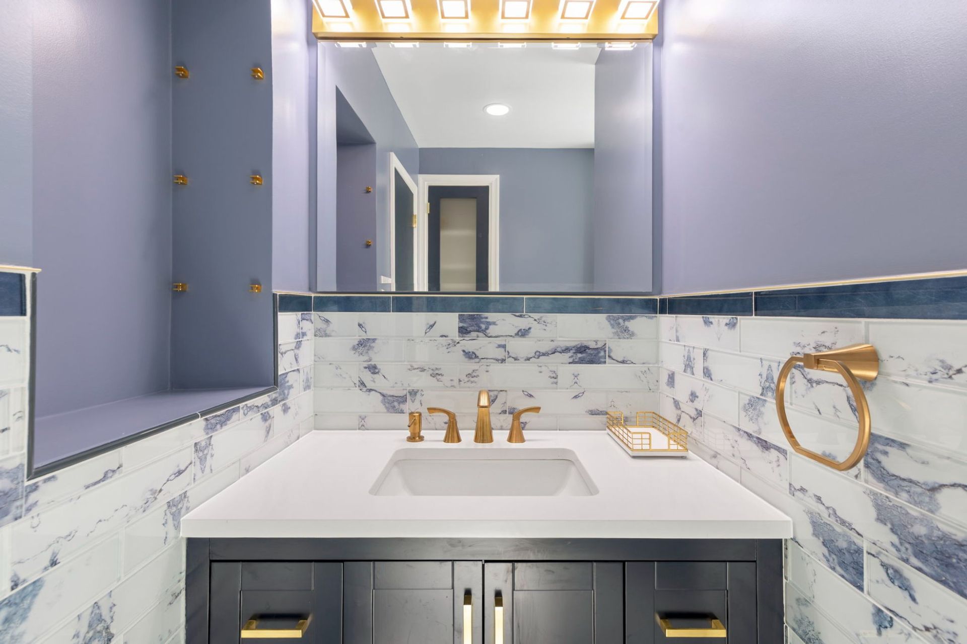 Bathroom vanity remodel with undermount sink, framed mirror, brushed gold light fixture, and marble tile by professional contractor Handyman on Demand serving Ellicott City MD