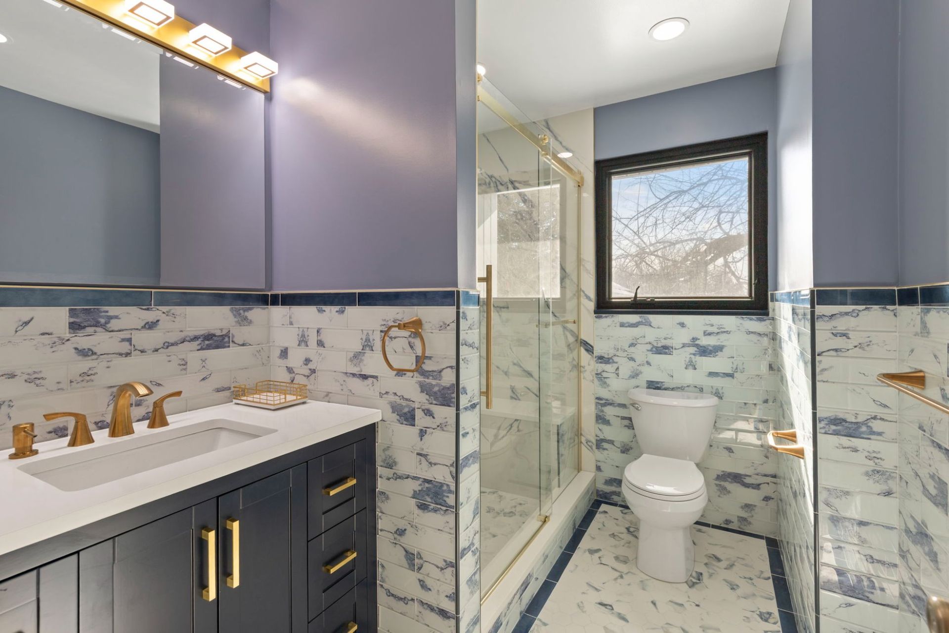Complete bathroom renovation featuring navy blue vanity, glass walk-in shower, and marble tile by licensed remodeling contractor Handyman on Demand serving Ellicott City MD