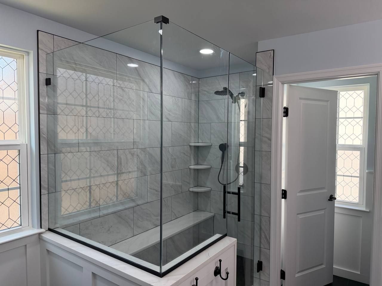 Custom shower remodel and bathroom renovation in Baltimore County MD — white marble tile, frameless glass enclosure, bench seat, and matte black hardware by Handyman on Demand