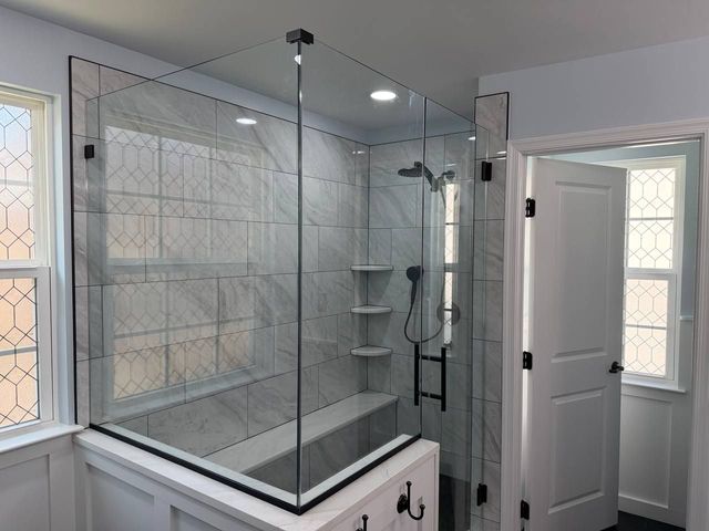 Frameless glass shower with bench seat and black hardware, a Handyman on Demand bathroom remodel