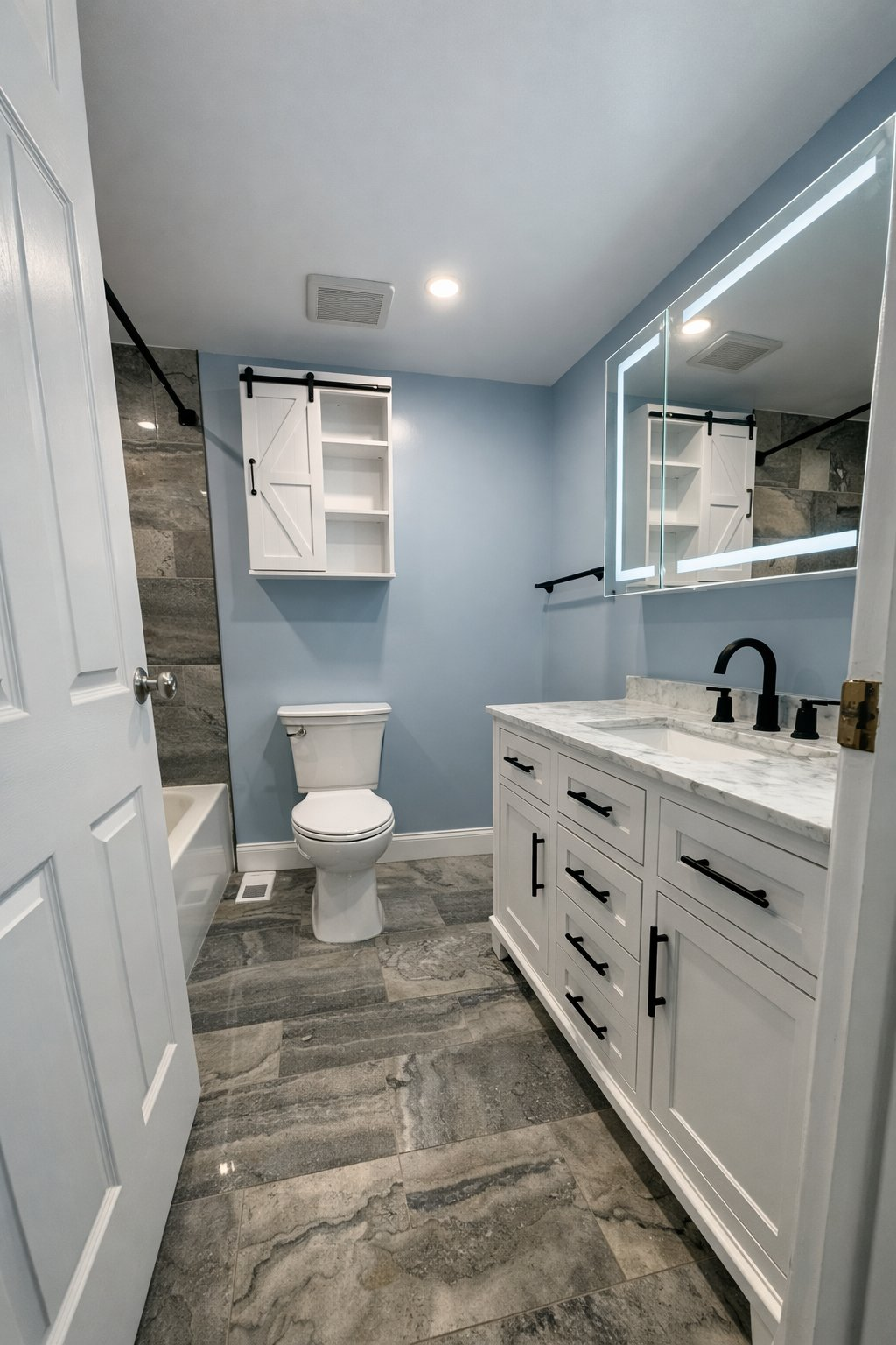 Full bathroom remodeling and renovation in Baltimore County MD with white shaker vanity, marble countertop, LED backlit mirror, sliding barn door cabinet, and gray stone tile floor by Handyman on Demand