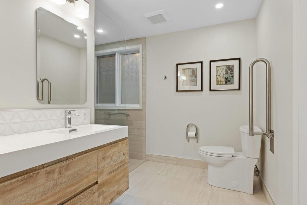 Bathroom with a wood vanity, toilet with a grab bar