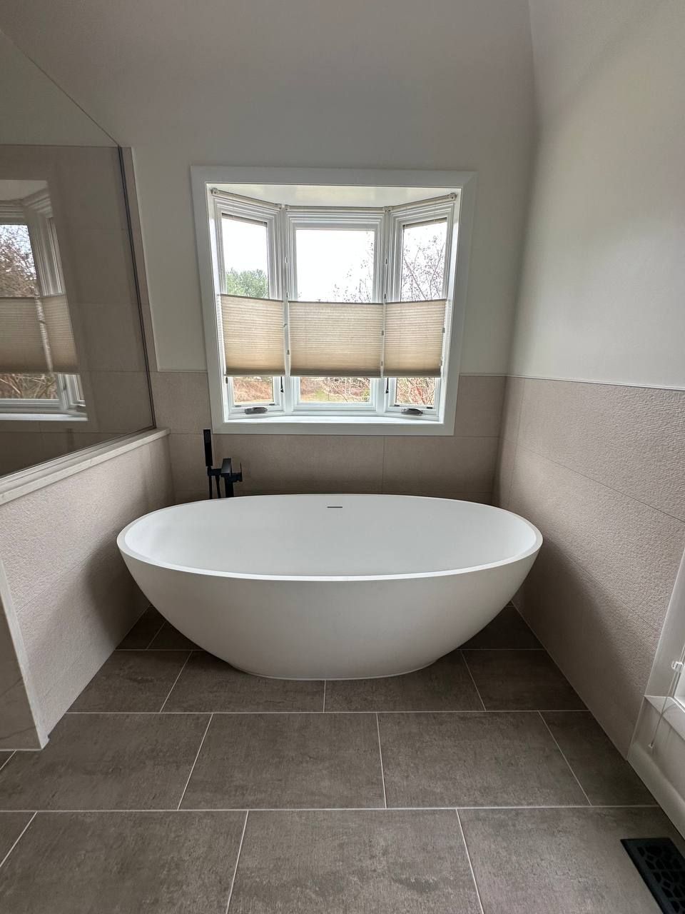 Freestanding soaking tub in a bay window with large-format tile – Urbana, MD