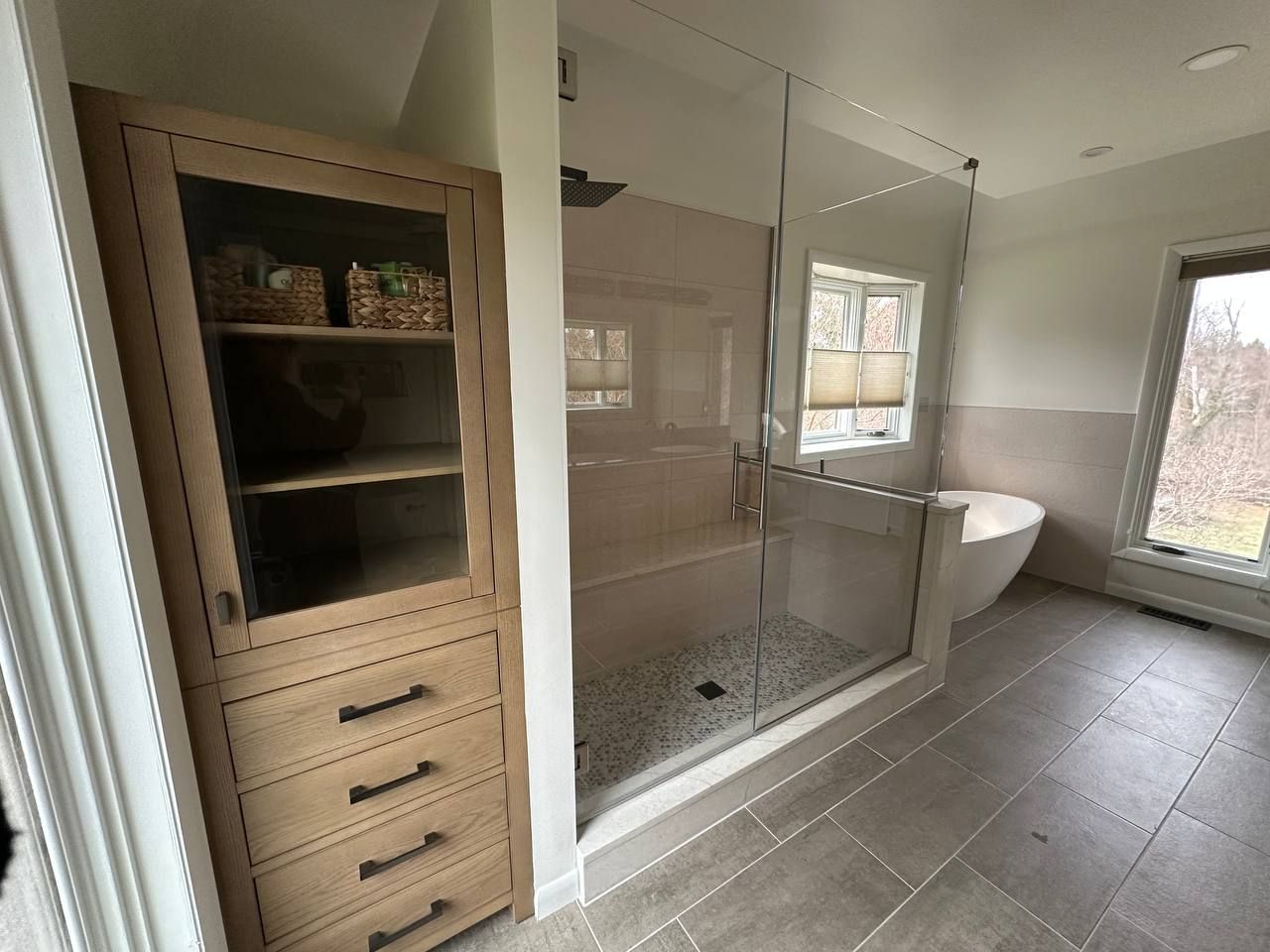 Professional master bathroom renovation in Baltimore County Maryland with custom glass shower, storage tower cabinet, and freestanding soaking tub by Handyman on Demand