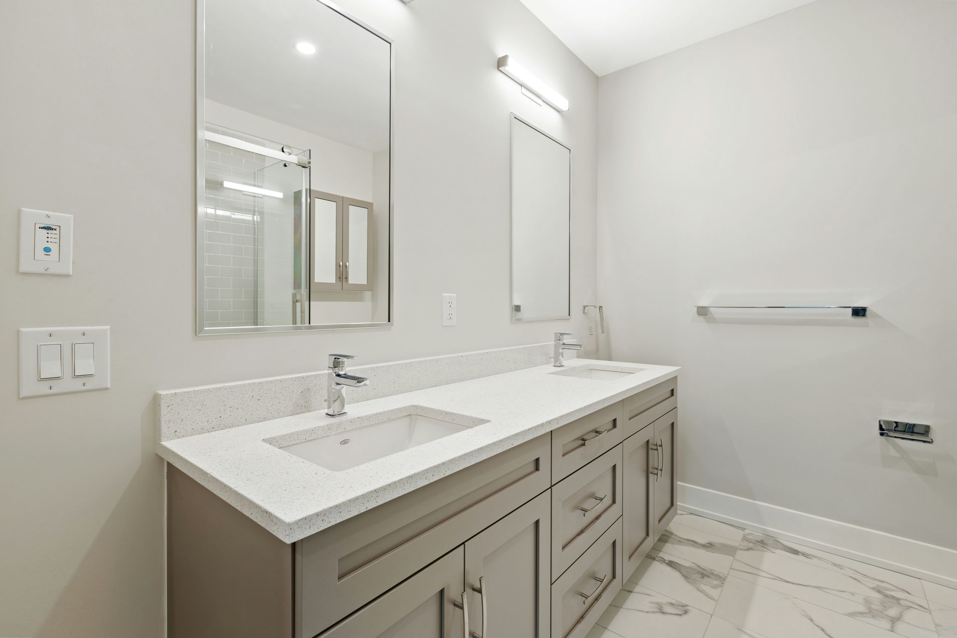 Bathroom with double vanity, grey cabinets, white countertop, and marble floors