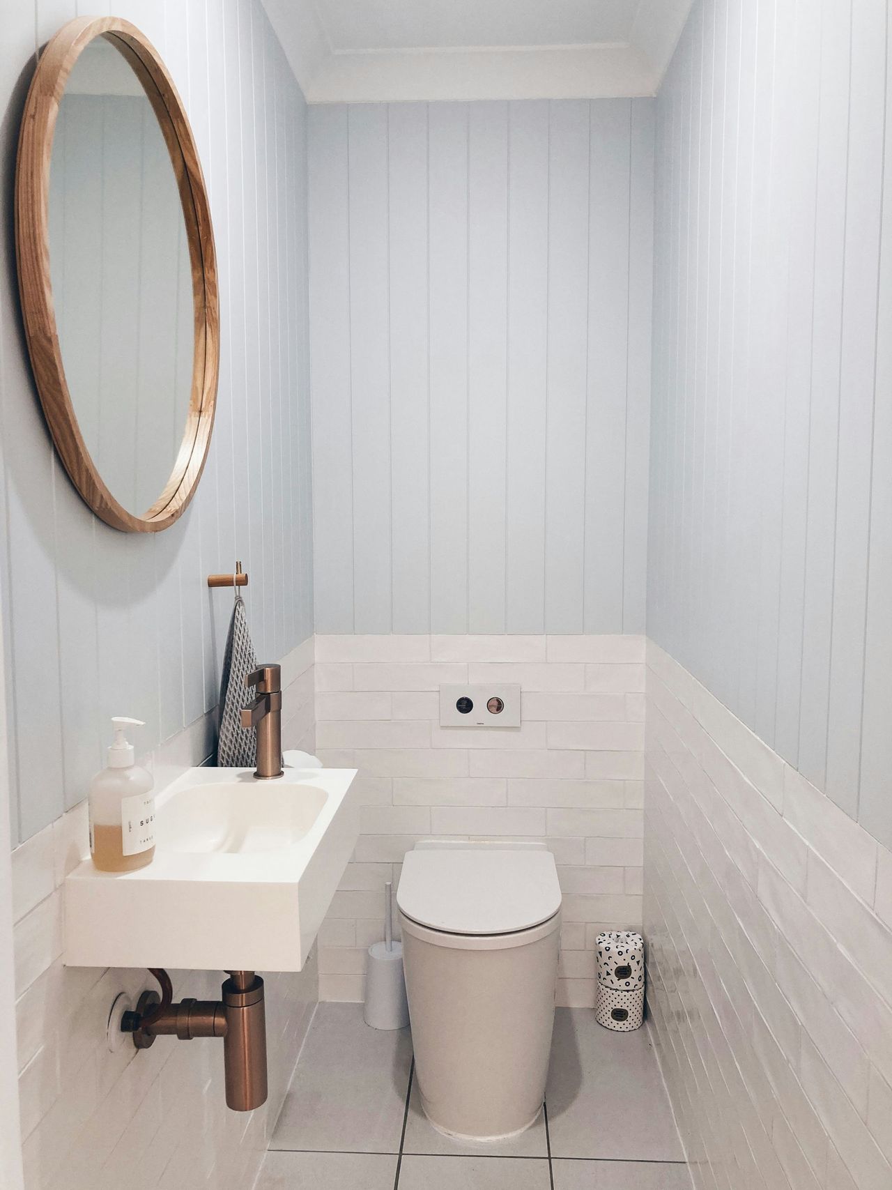 Powder room with shiplap walls, wall-mount sink and round wood mirror – Anne Arundel County, MD