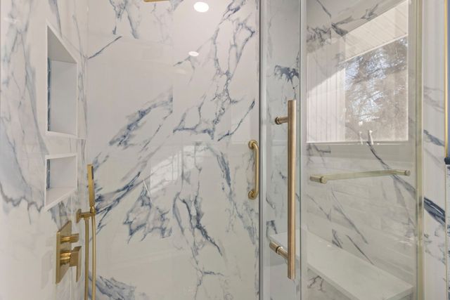 Walk-in shower with marble slab tile and gold fixtures