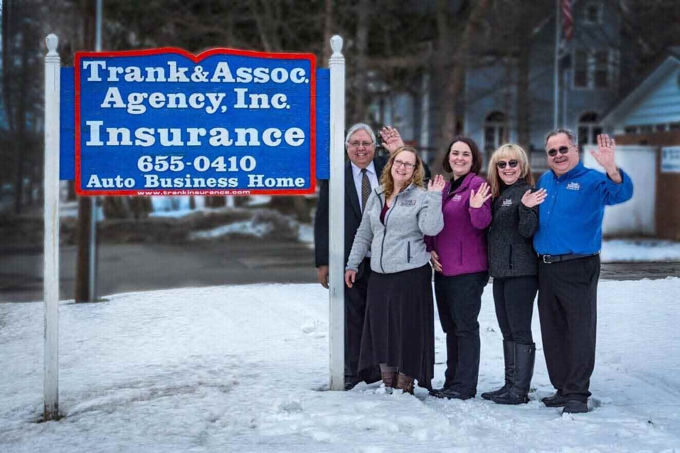 Five people wave in front of a blue 