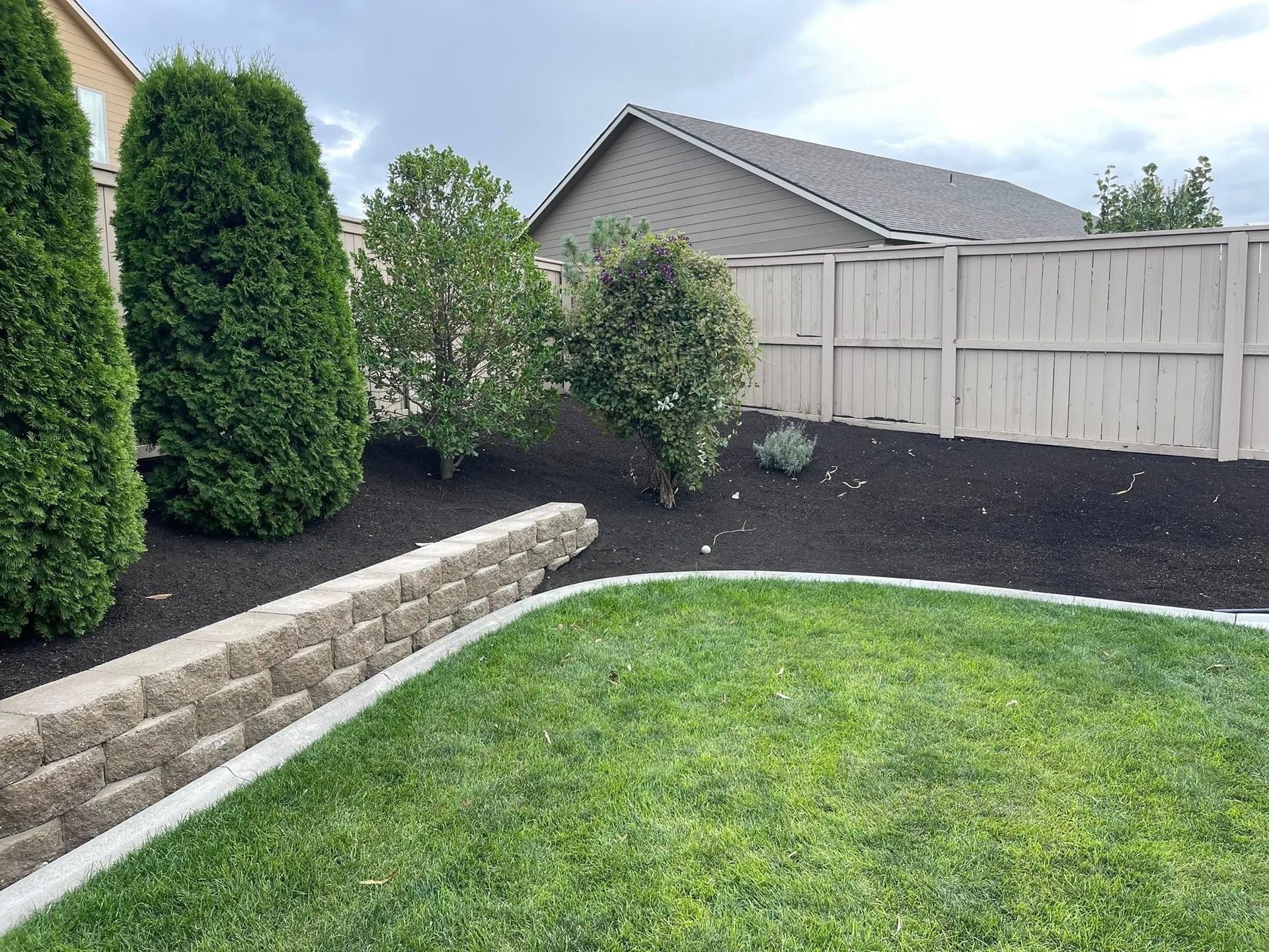 A backyard with a stone retaining wall.
