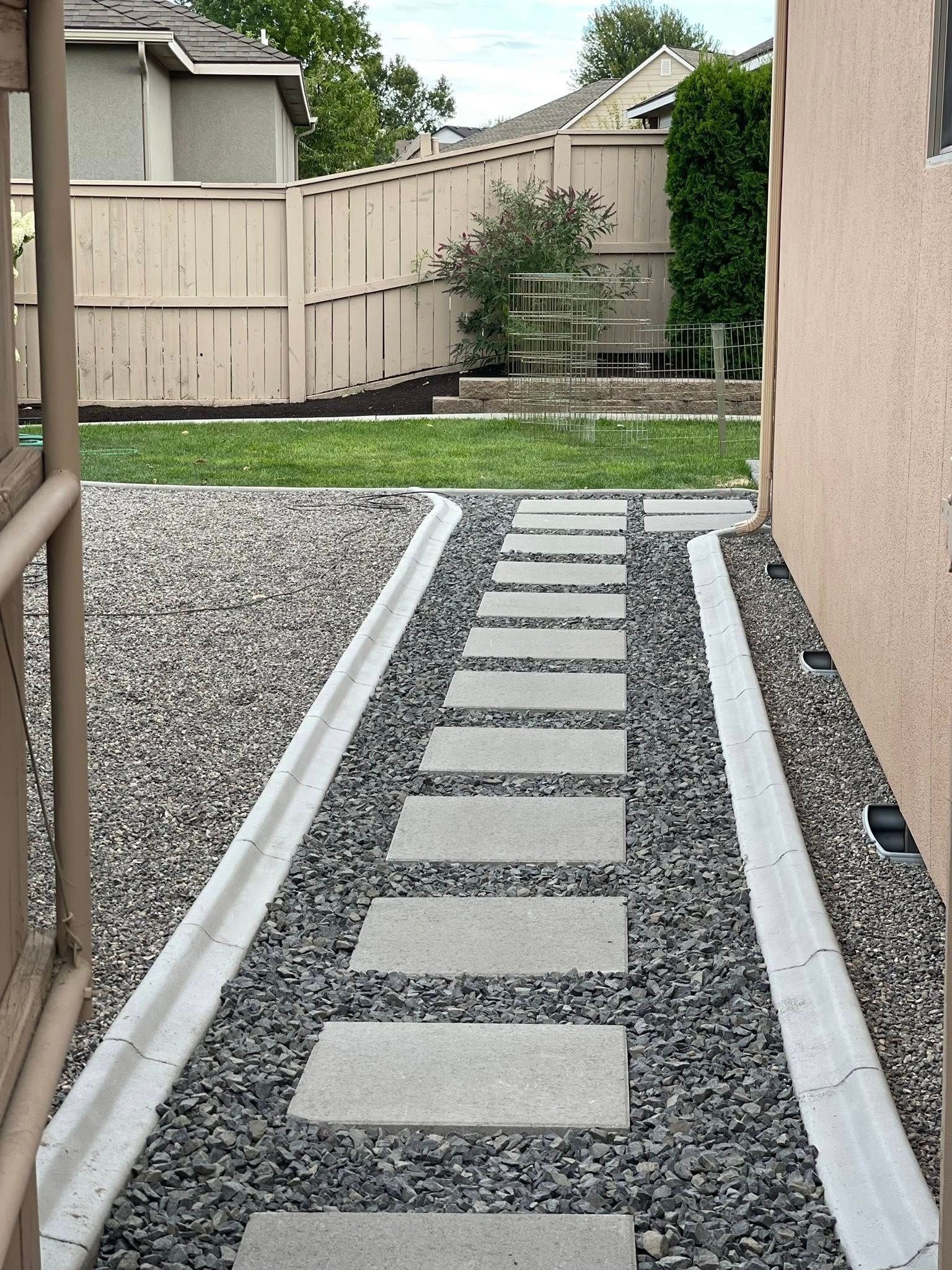 A stone paver path leads between grey gravel beds.