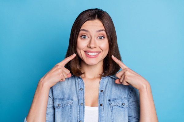 Frau zeigt ihr Lächeln nach erfolgreichem Bleaching