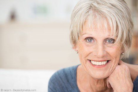 Lächelnde ältere Frau mit festen Zahnimplantaten in Berlin